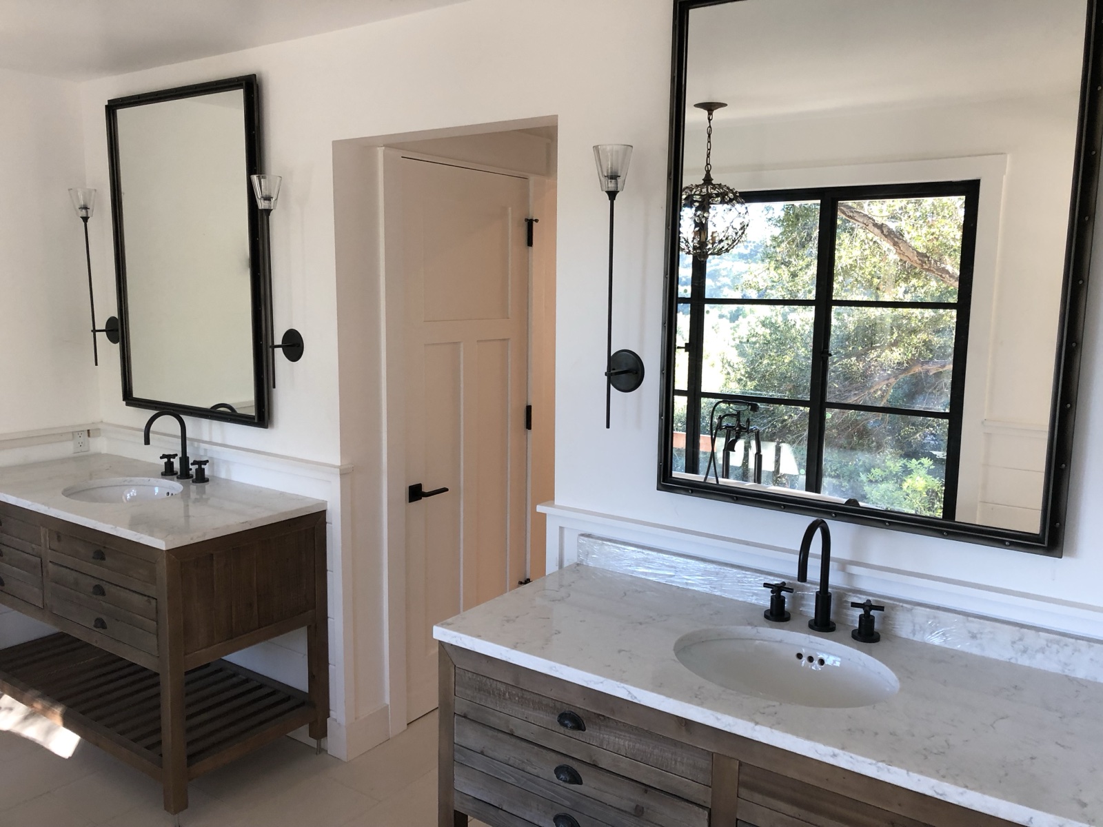 Luxury master bathroom with dual vanities, marble countertops, and black-frame mirrors