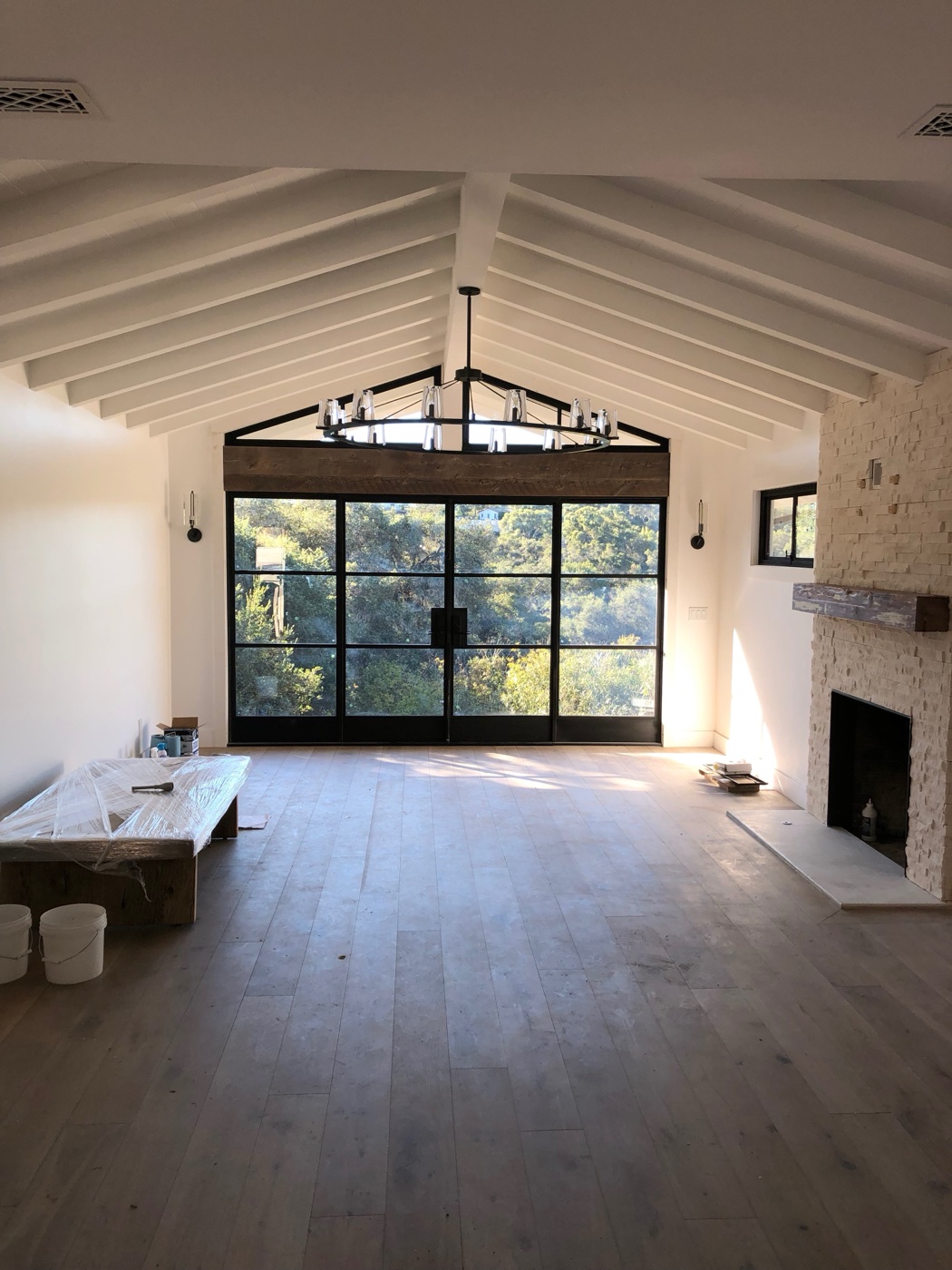 Custom great room with vaulted beam ceiling, steel-frame glass doors, and stone fireplace